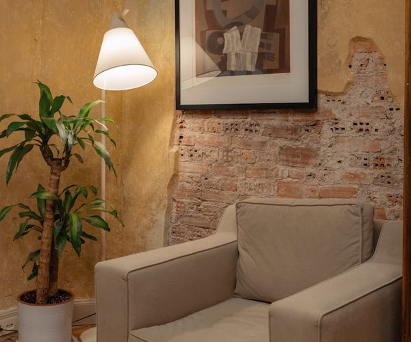 Cozy room corner with a comfortable chair and a plant in soft light.